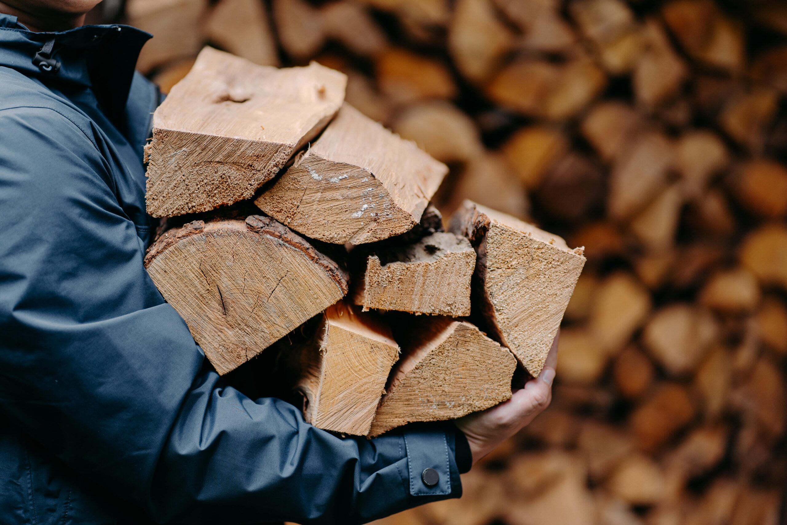 Man carrying firewood by county logs and coal