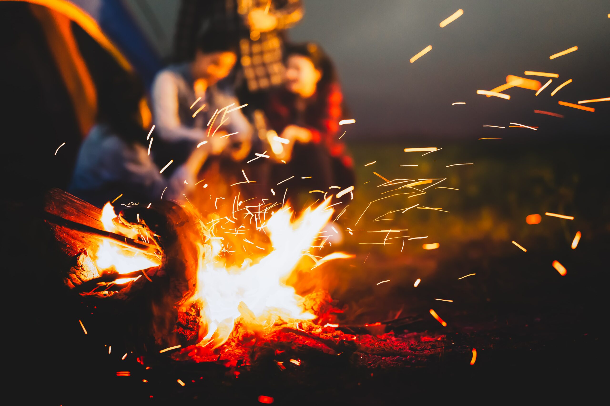 people huddled around a bonfire keeping warm - using firewood logs from County Logs and Coal