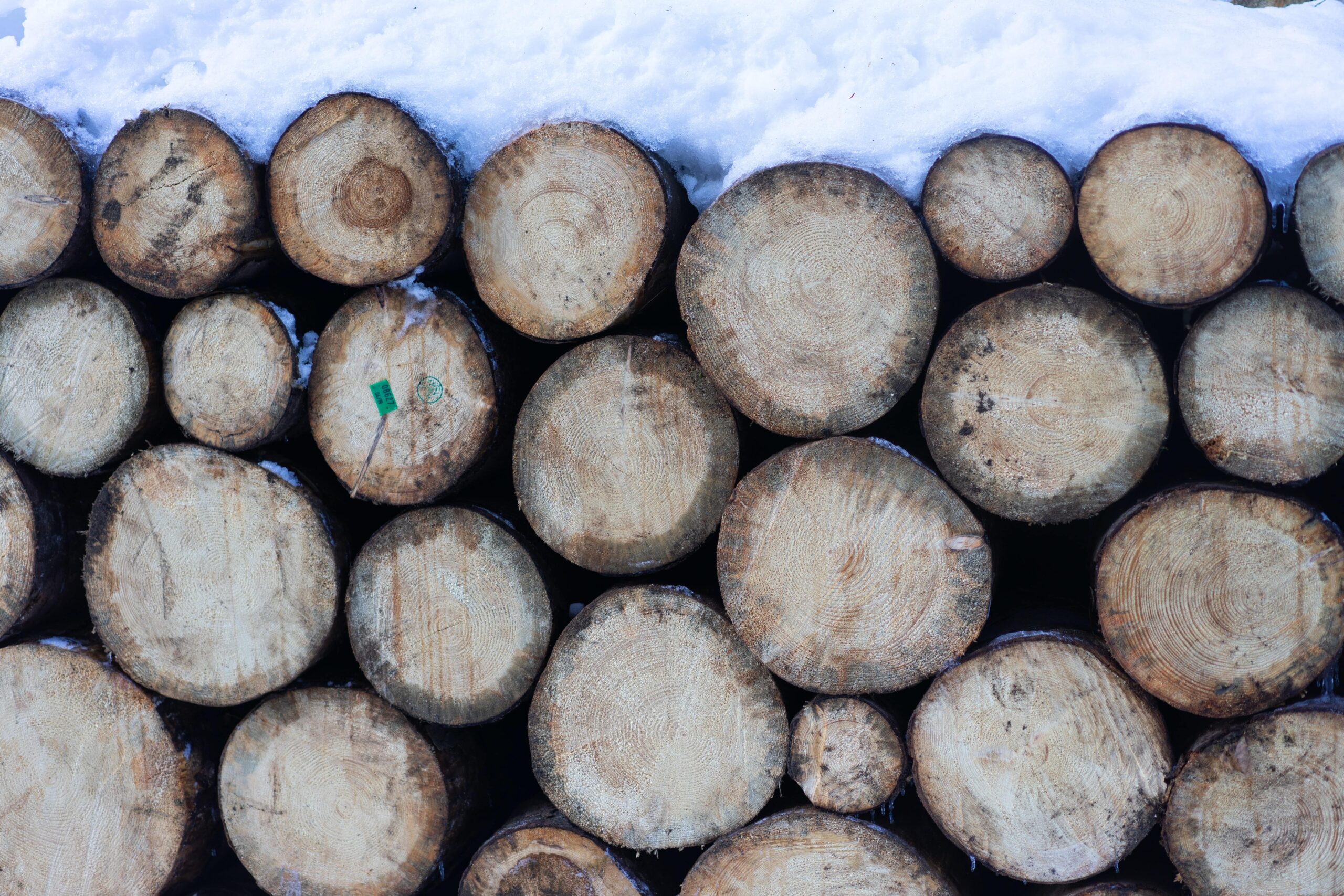 winter firewood stacked outside during winter with snow on top - as advised by County Logs and Coal